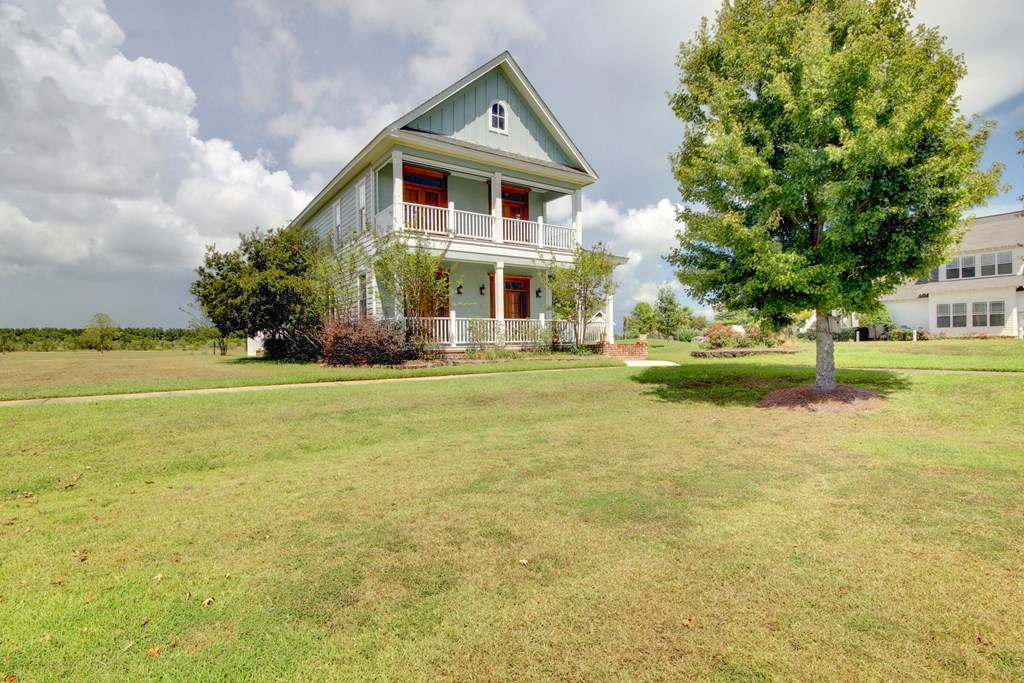 a house with a large lawn and a tree in front of it