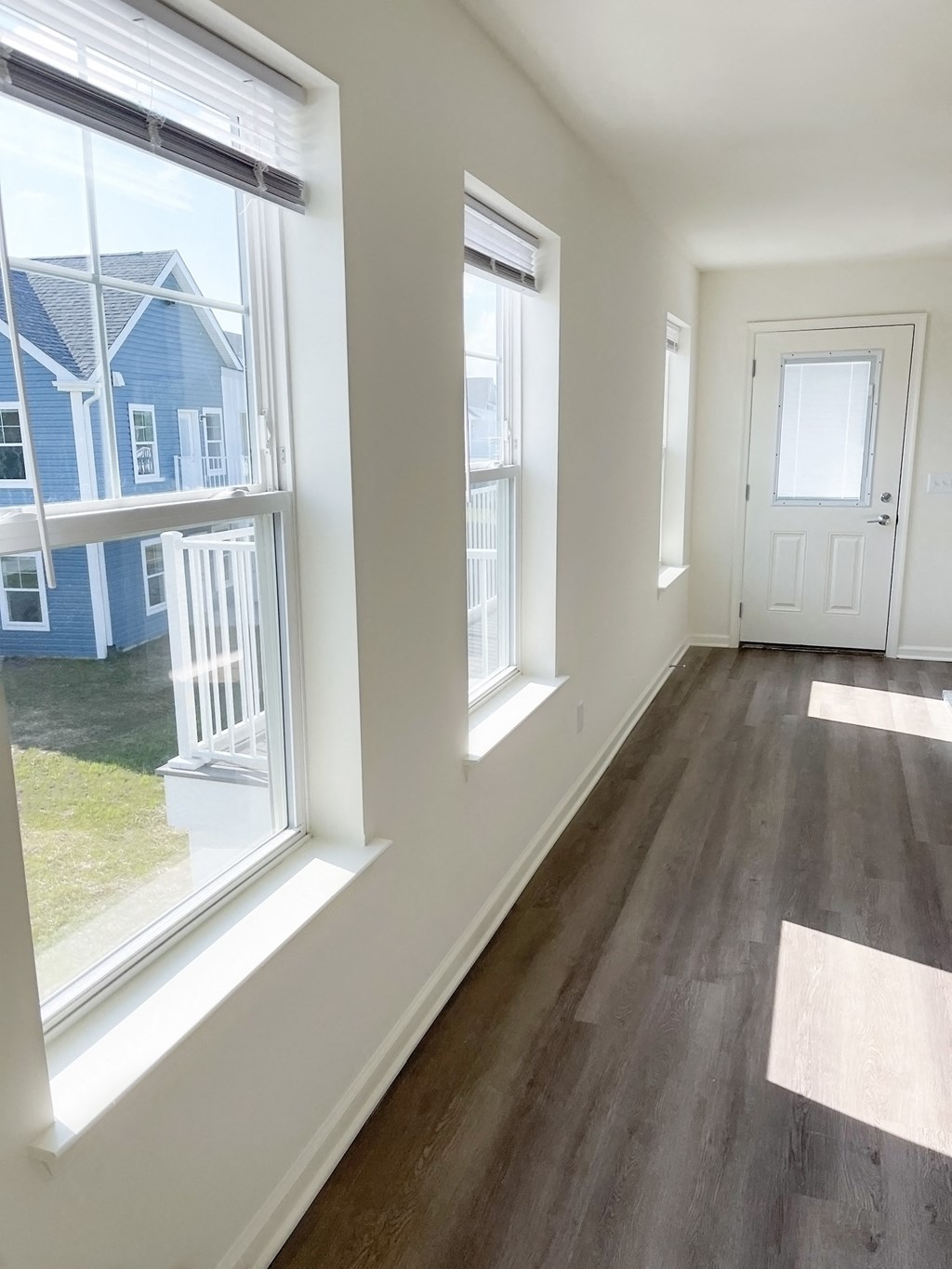 an empty living room with large windows and a door