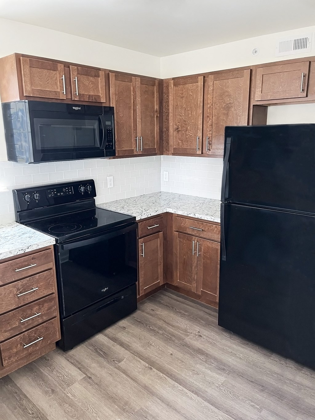 an empty kitchen with black appliances and wooden cabinets