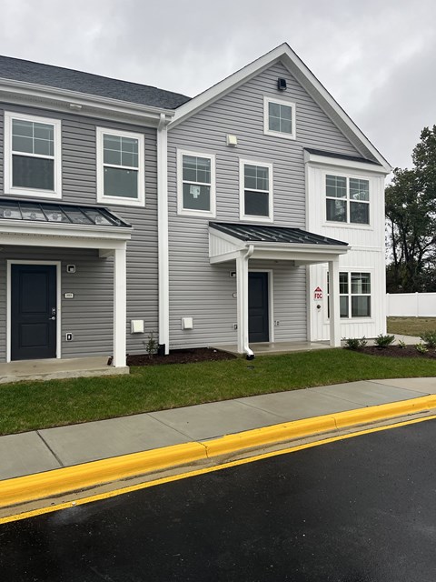 a gray house with white siding and a black door