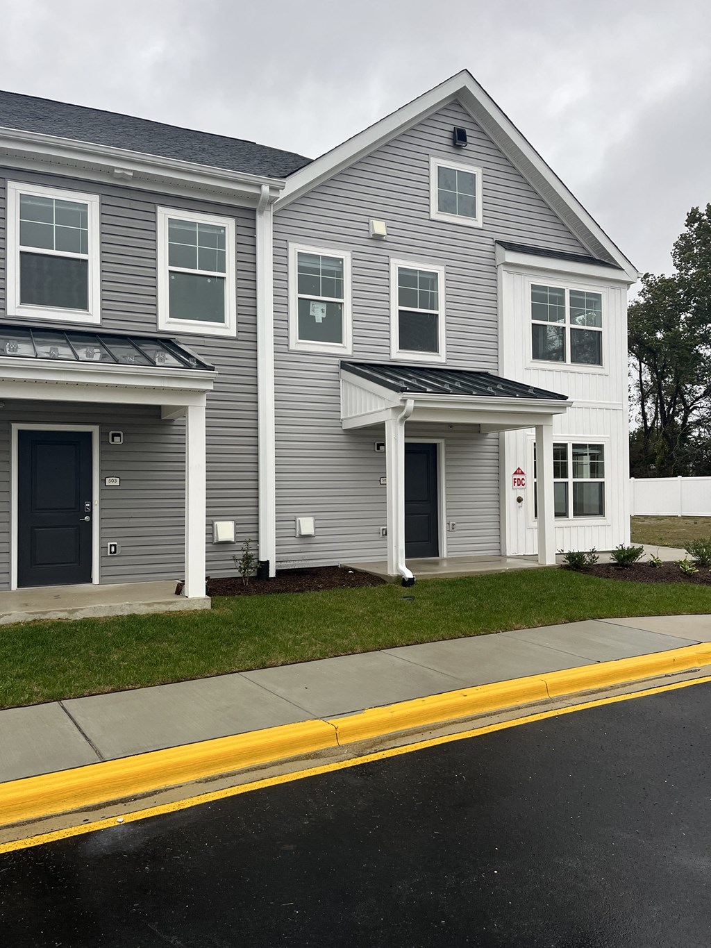 a gray house with white siding and a black door