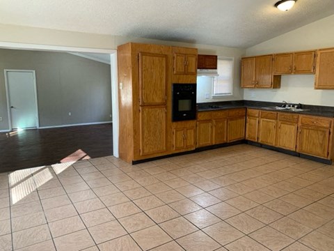 an empty kitchen with wooden cabinets and a tile floor