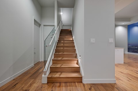 A long hallway with a wooden staircase and white walls.