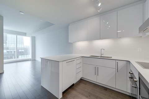 A modern kitchen with white cabinets and a wooden floor.