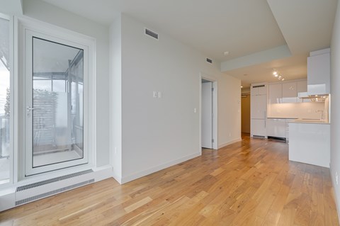 A spacious room with wooden floors and white walls.
