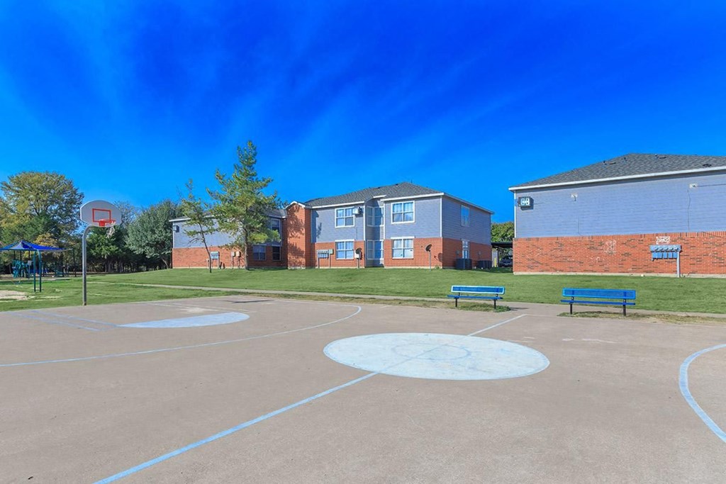 a basketball court with benches in front of two brick buildings