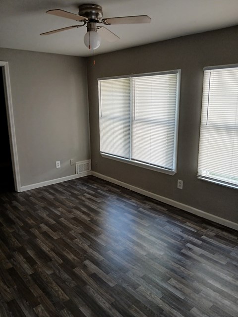 an empty living room with wood floors and a ceiling fan