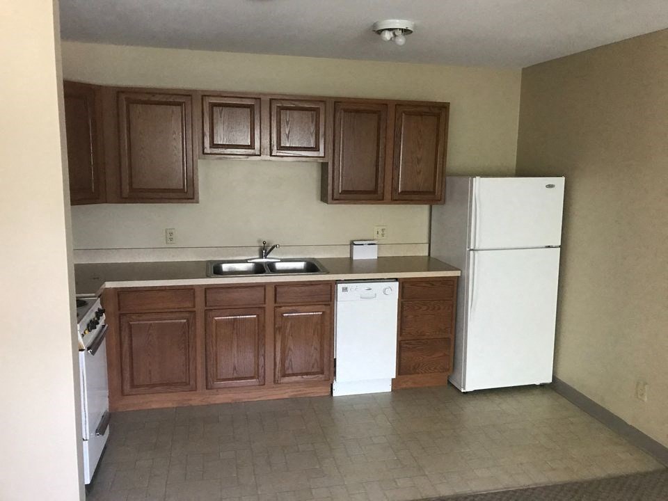 an empty kitchen with a refrigerator and a sink