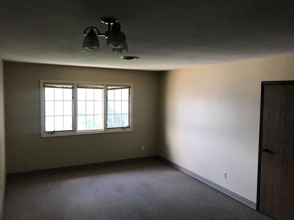 an empty room with a window and ceiling lights