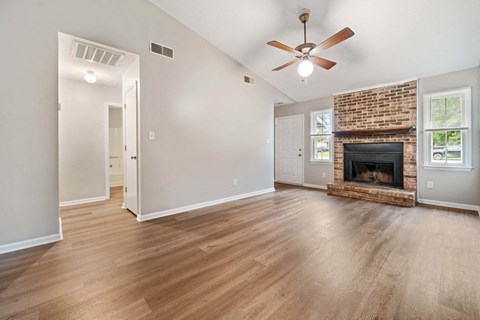 an empty living room with a fireplace and a ceiling fan