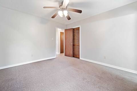 A room with a ceiling fan and carpeted floor.