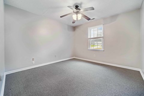 A room with a ceiling fan and a window with blinds.