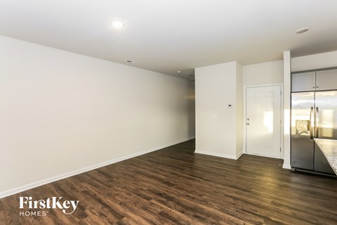 A spacious room with wooden flooring and white walls, with a door leading to another room.