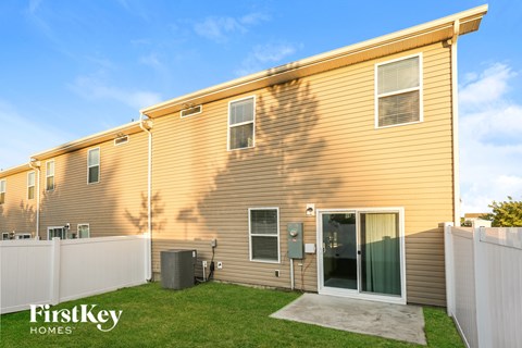 A FirstKey Homes residential building with a fence and a green lawn.