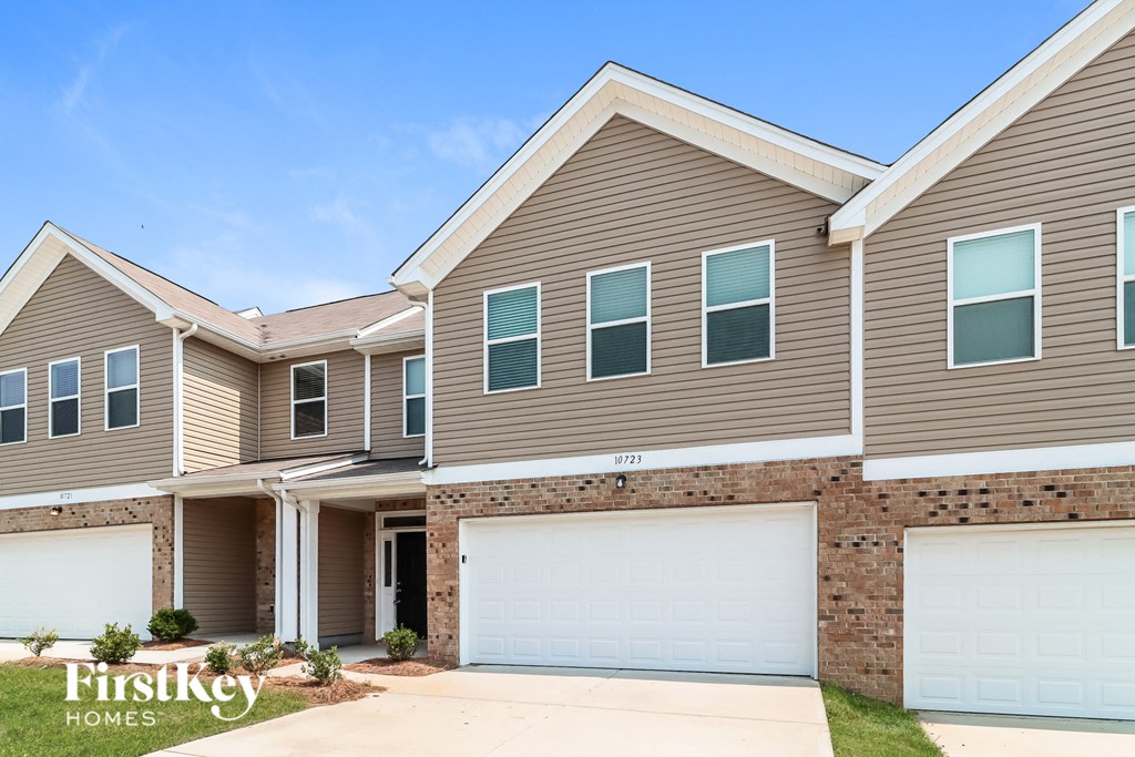 a beige and brick house with two garage doors