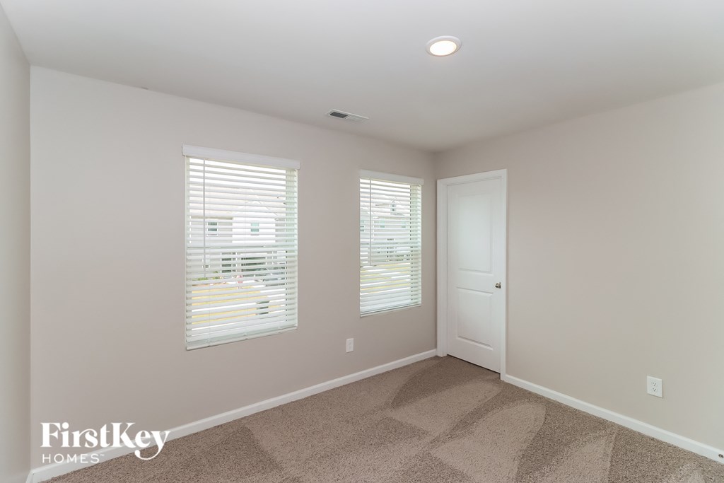 a bedroom with two windows and a door and a carpeted floor