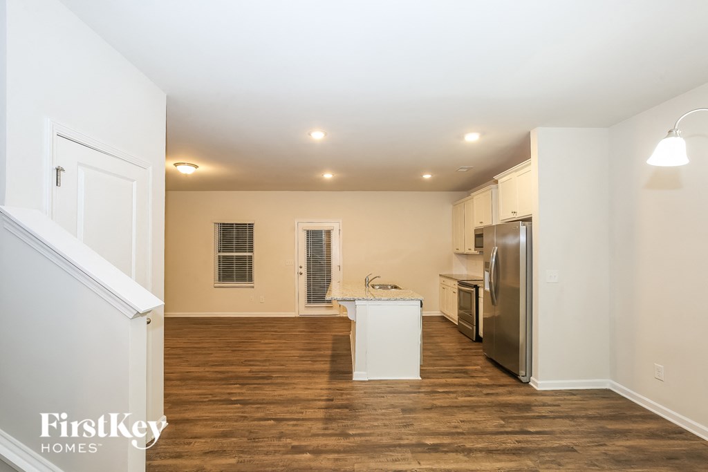 A kitchen with white cabinets and a wooden floor.