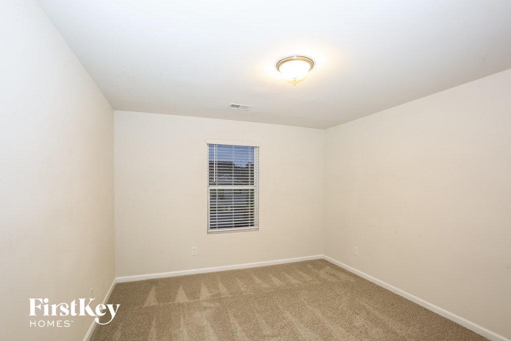 A room with a carpeted floor and a window with blinds.