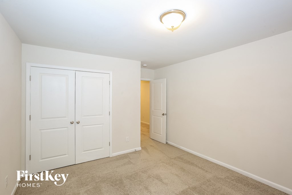 A bedroom with a carpeted floor and a white door.