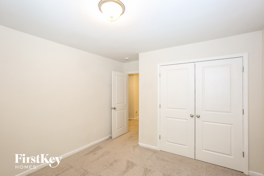 A bedroom with a white door and a carpeted floor.