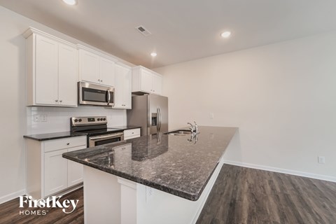 A kitchen with a granite countertop and a stainless steel refrigerator.