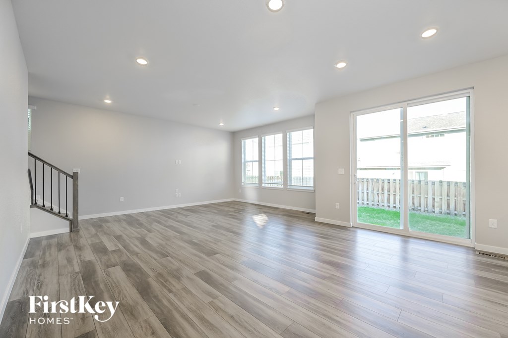 A spacious room with wooden flooring and a sliding glass door leading to a balcony.