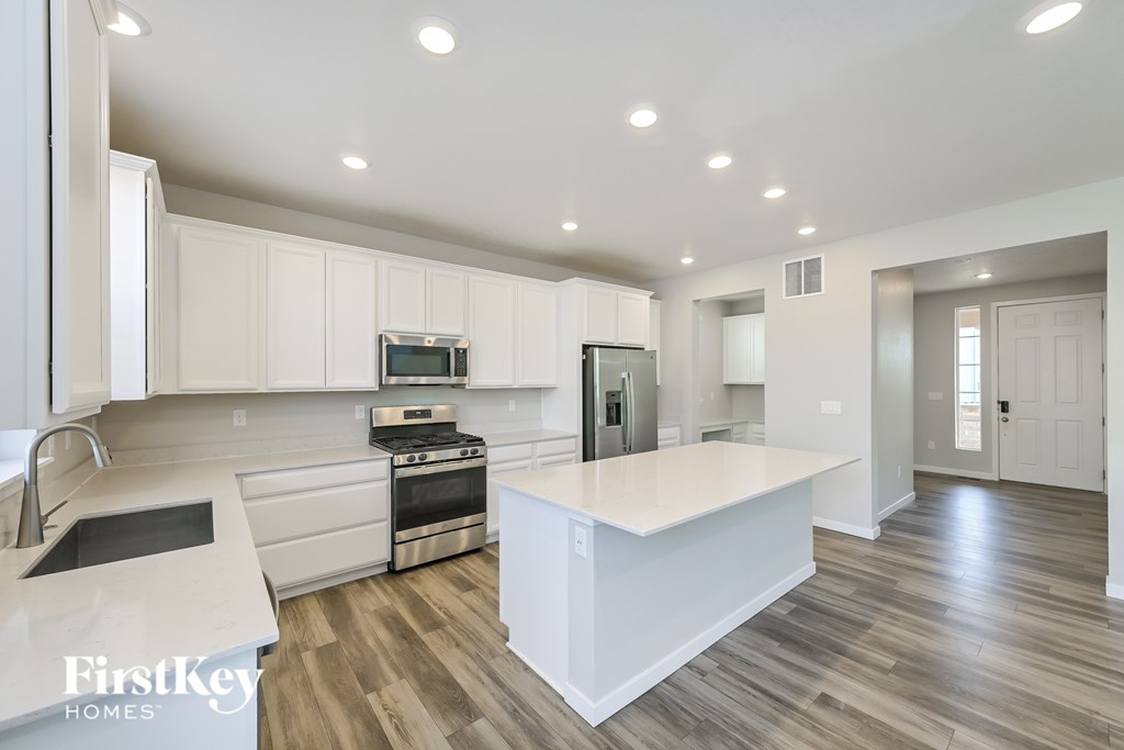 A modern kitchen with a white island and stainless steel appliances.