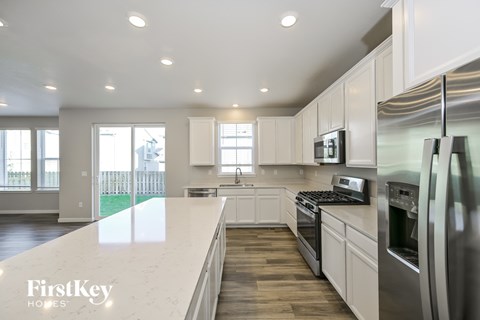 A modern kitchen with a stainless steel refrigerator and a marble countertop.