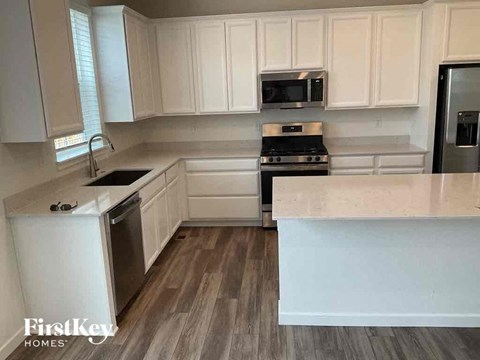 A kitchen with white cabinets and a wooden floor.