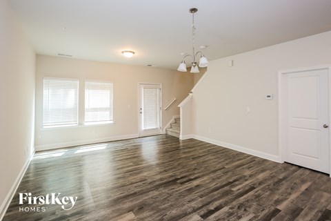 A spacious room with wooden floors and a staircase.
