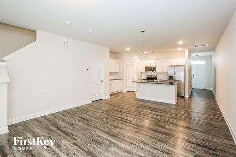 A spacious kitchen with white cabinets and a wooden floor.