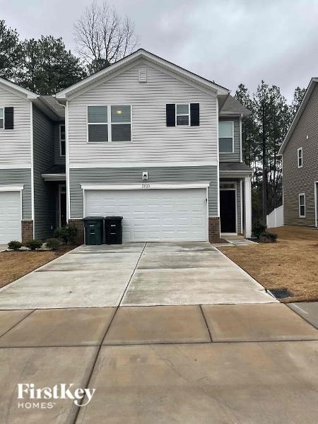 A two-story house with a garage and a driveway in front.