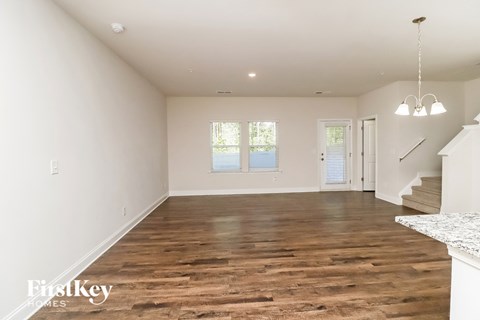A spacious room with wooden flooring and white walls.