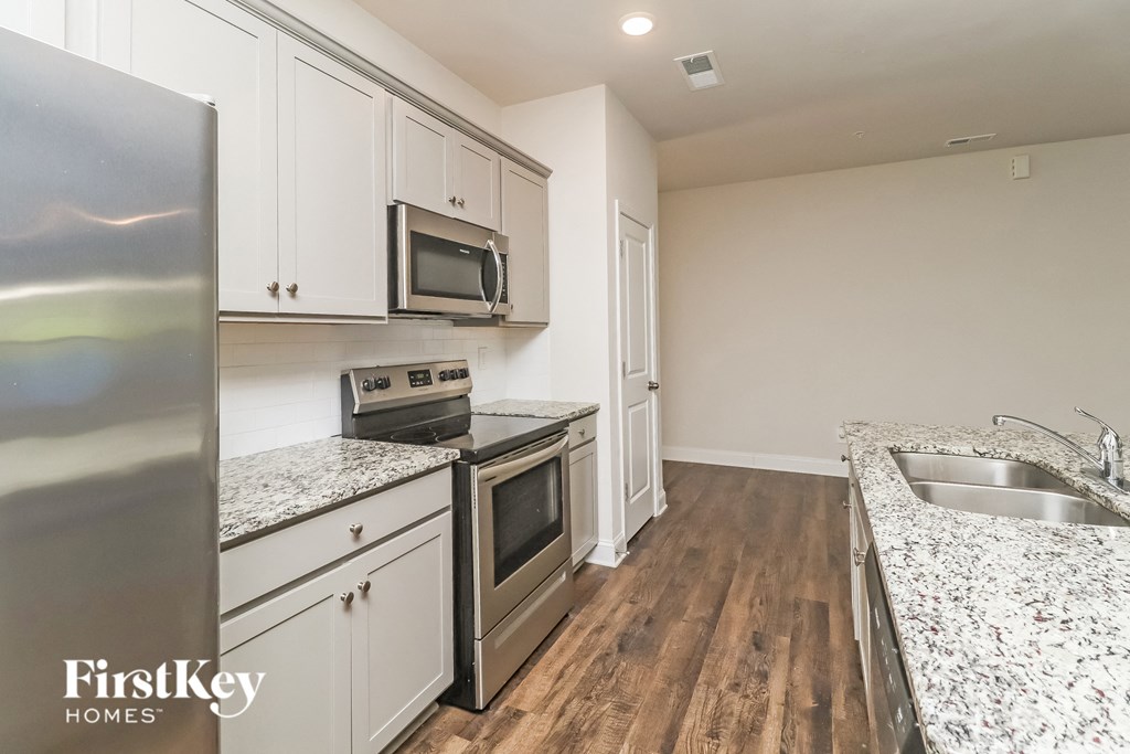 A kitchen with a refrigerator, microwave, oven, and sink.