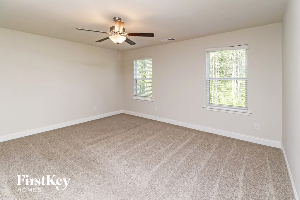 A room with a carpet floor and a ceiling fan.