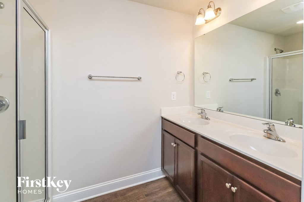 A bathroom with a white sink and brown cabinets.