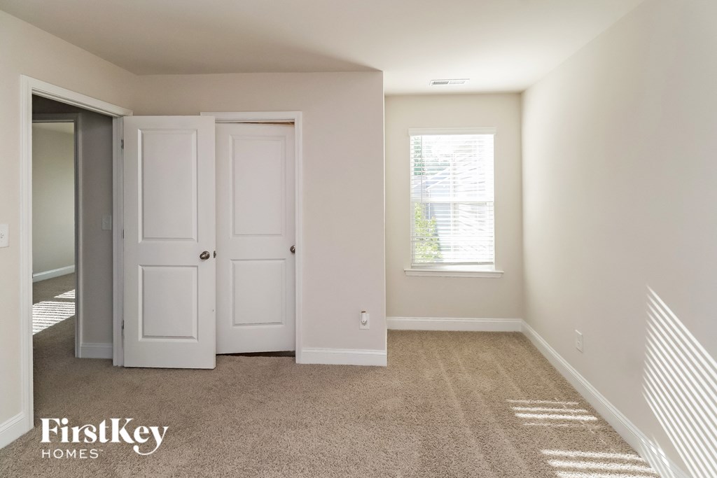 A room with a carpeted floor and a window with blinds.