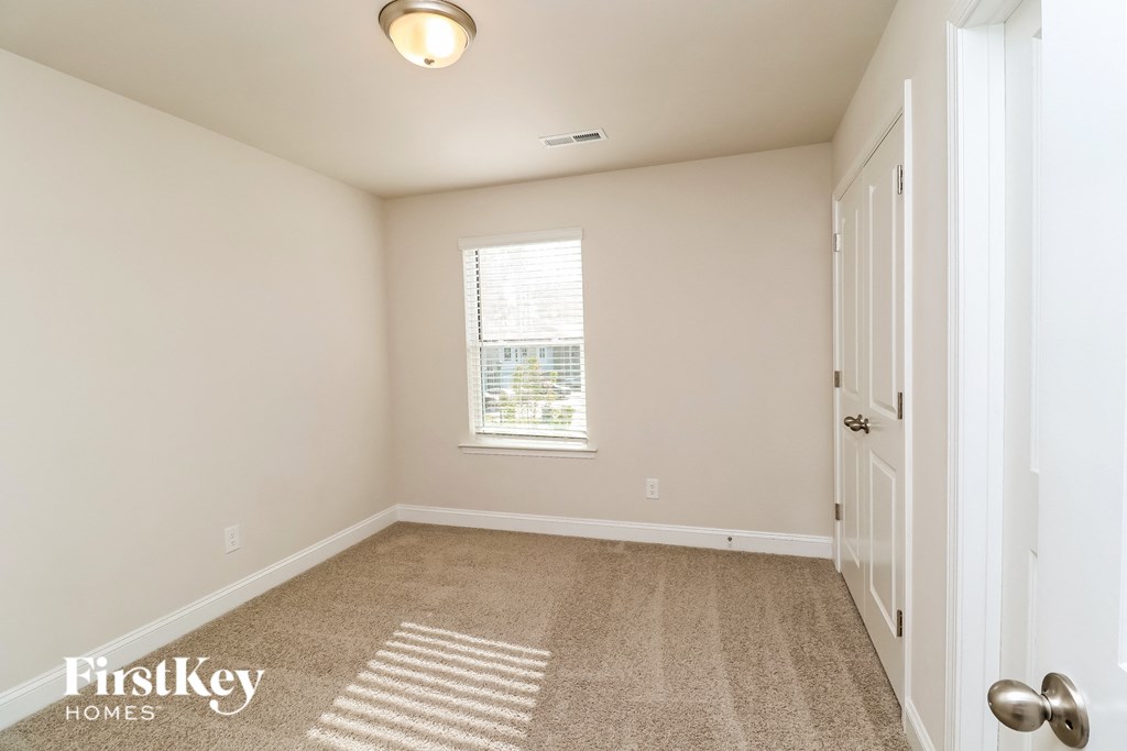A room with a carpeted floor and a door on the right side.