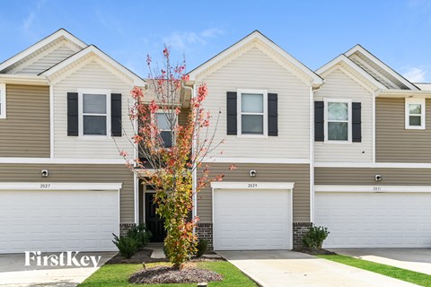 a white and brown house with two garage doors