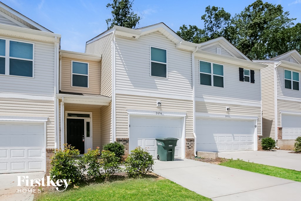A row of houses with the first one having a garage door open.