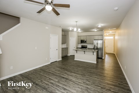 A spacious room with a kitchen area in the background.