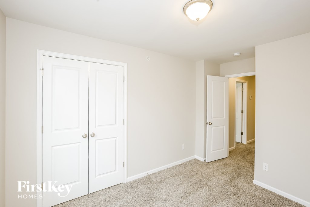 A carpeted room with a white door and a light on the ceiling.
