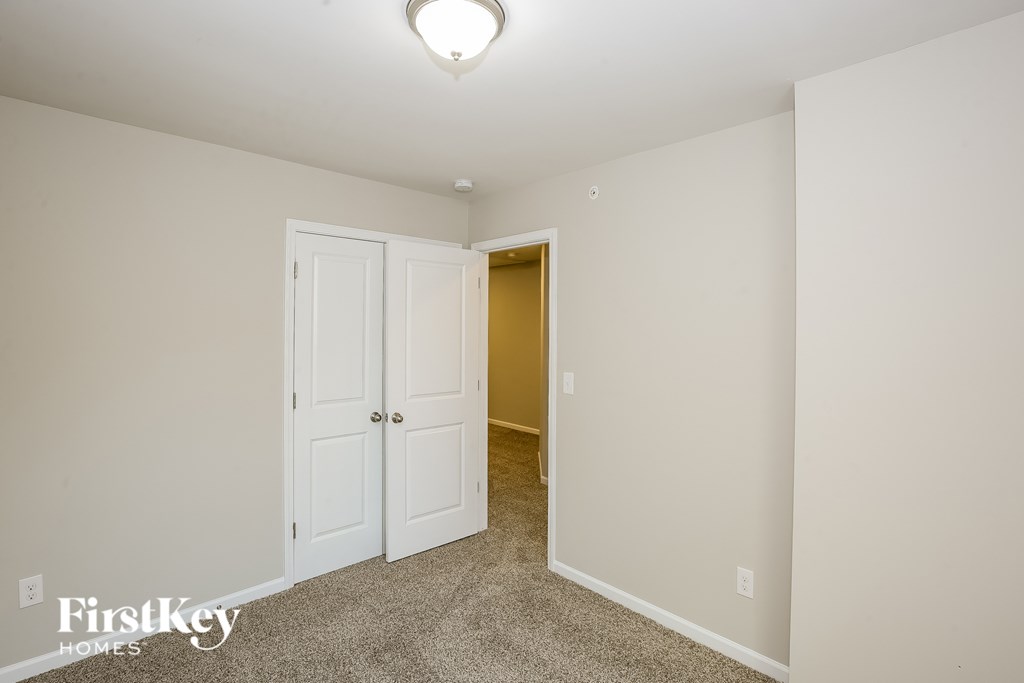 A carpeted room with a white door and a light on the ceiling.