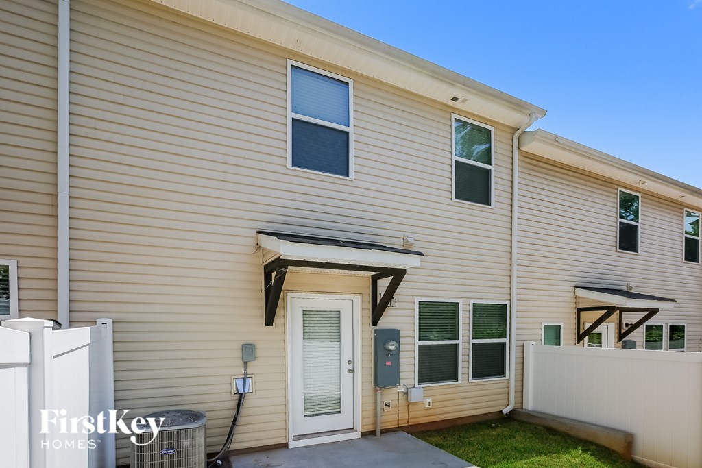 A beige house with a white fence and a small porch.