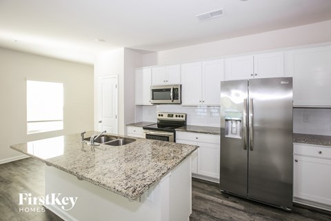 a white kitchen with stainless steel appliances and granite counter tops
