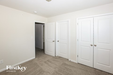 a bedroom with three closets and a door to a hallway