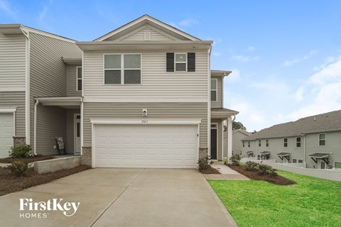 a tan house with a white garage door on a sidewalk