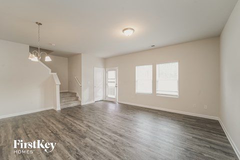 a spacious living room with white walls and wood floors