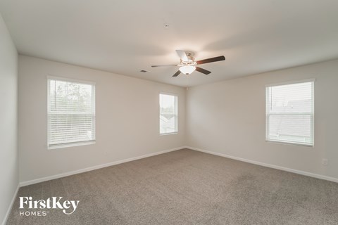 a bedroom with a ceiling fan and two windows