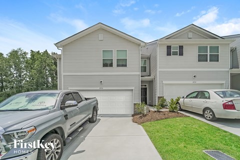 A silver truck is parked in front of a two-story house.
